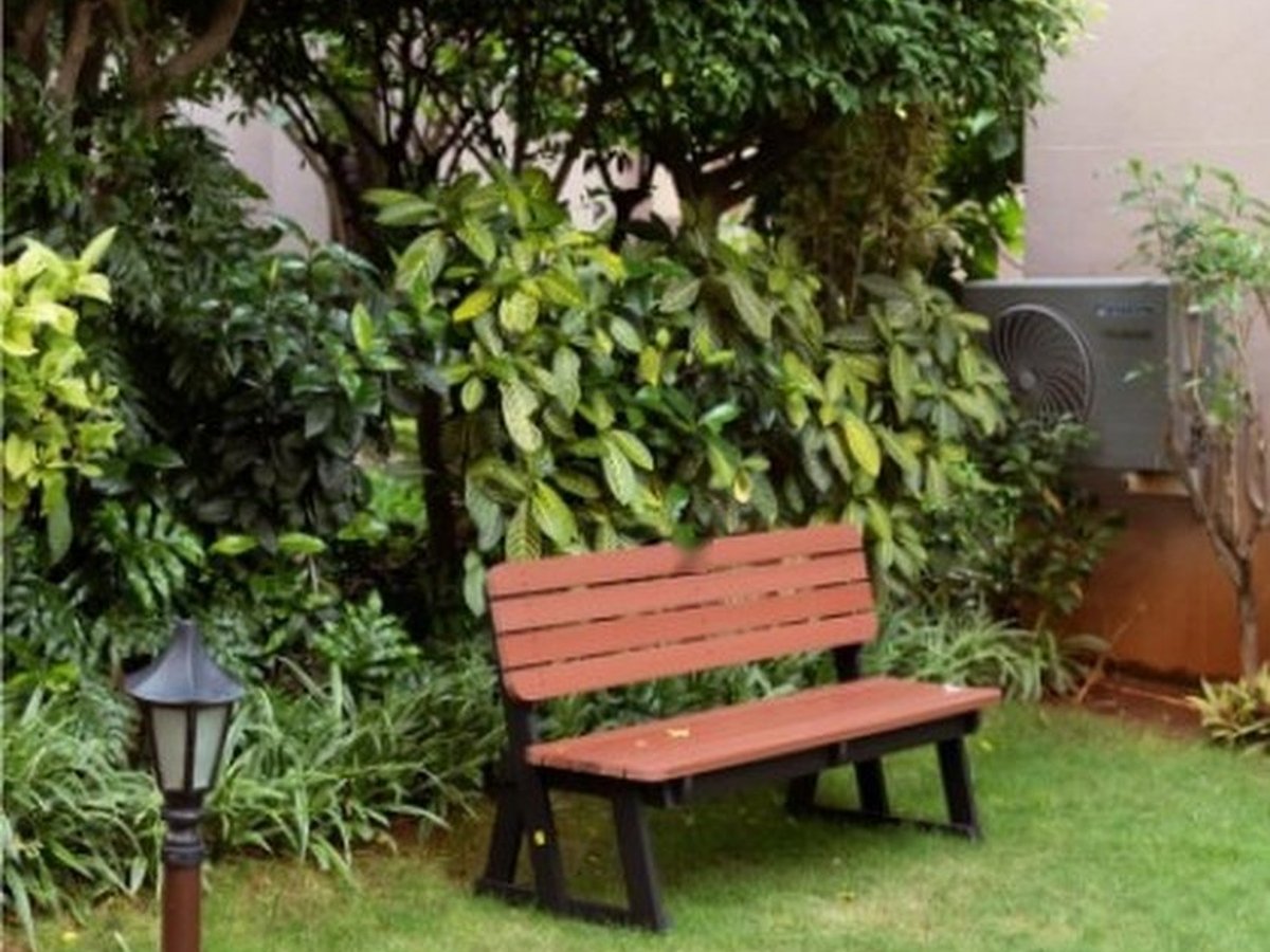 Red-brown KalpWud polymer-lumber garden bench on a lawn beside a lamp post